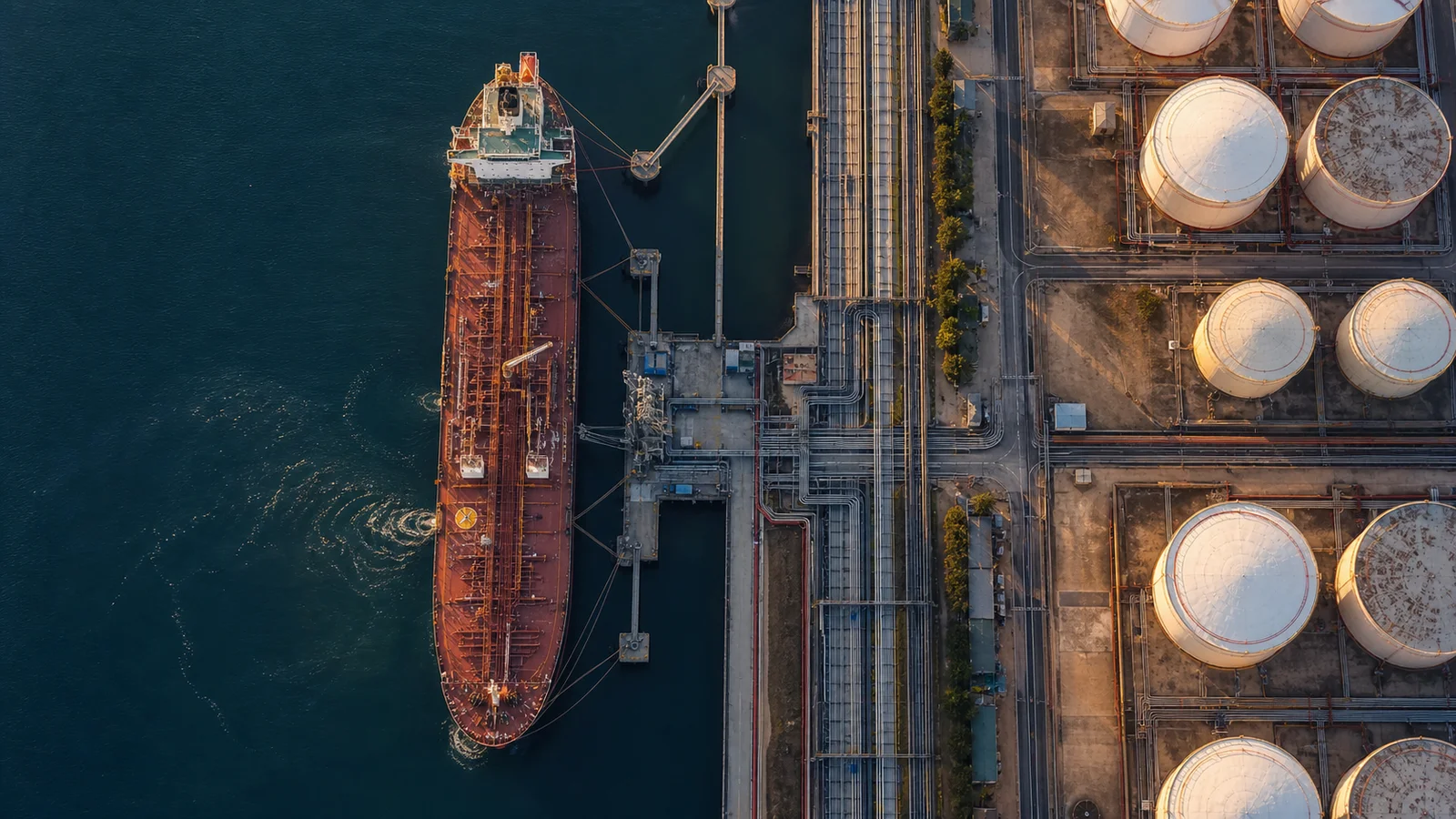 Crude oil tanker beside a jetty, pipelines and storage tanks