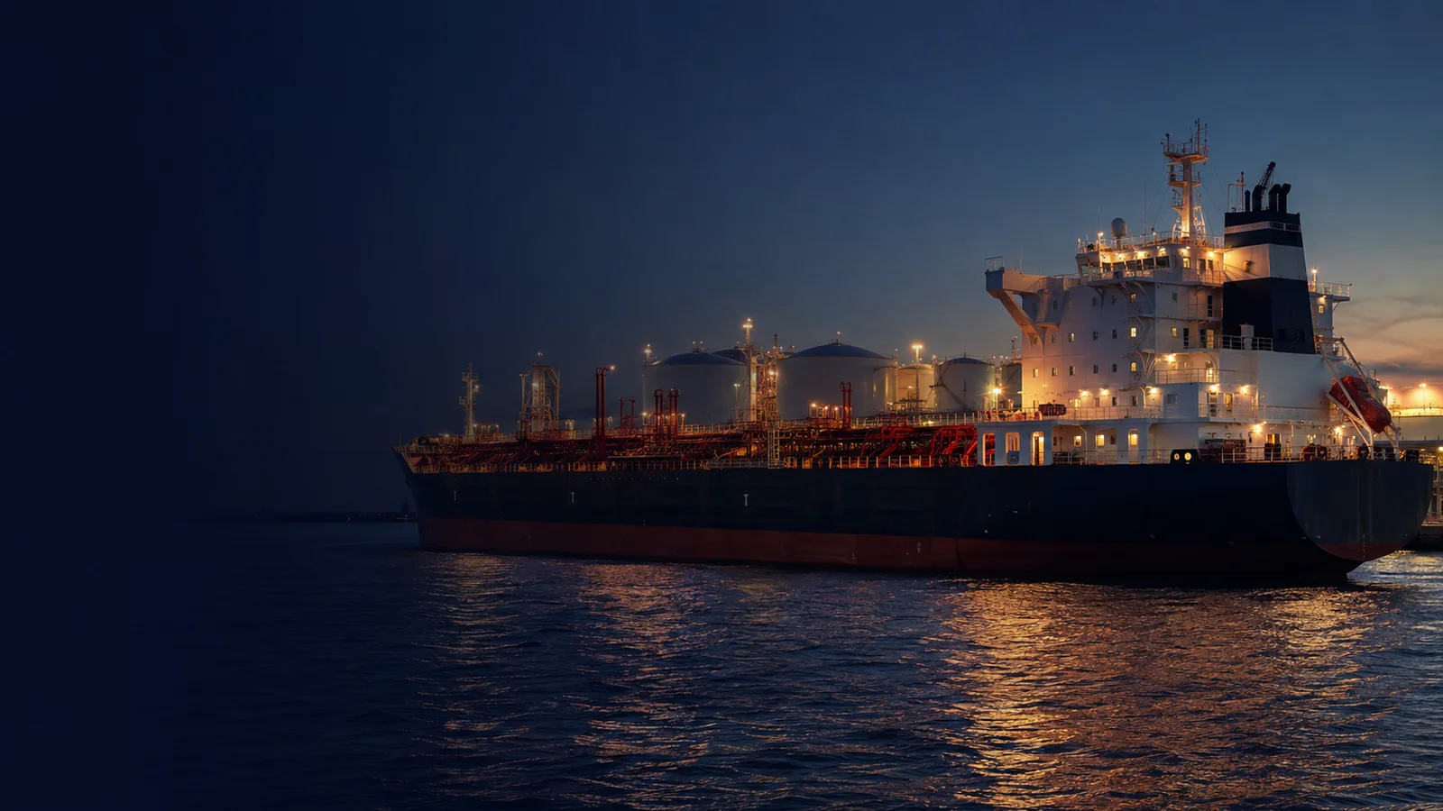Red-deck product tanker alongside an illuminated energy loading terminal